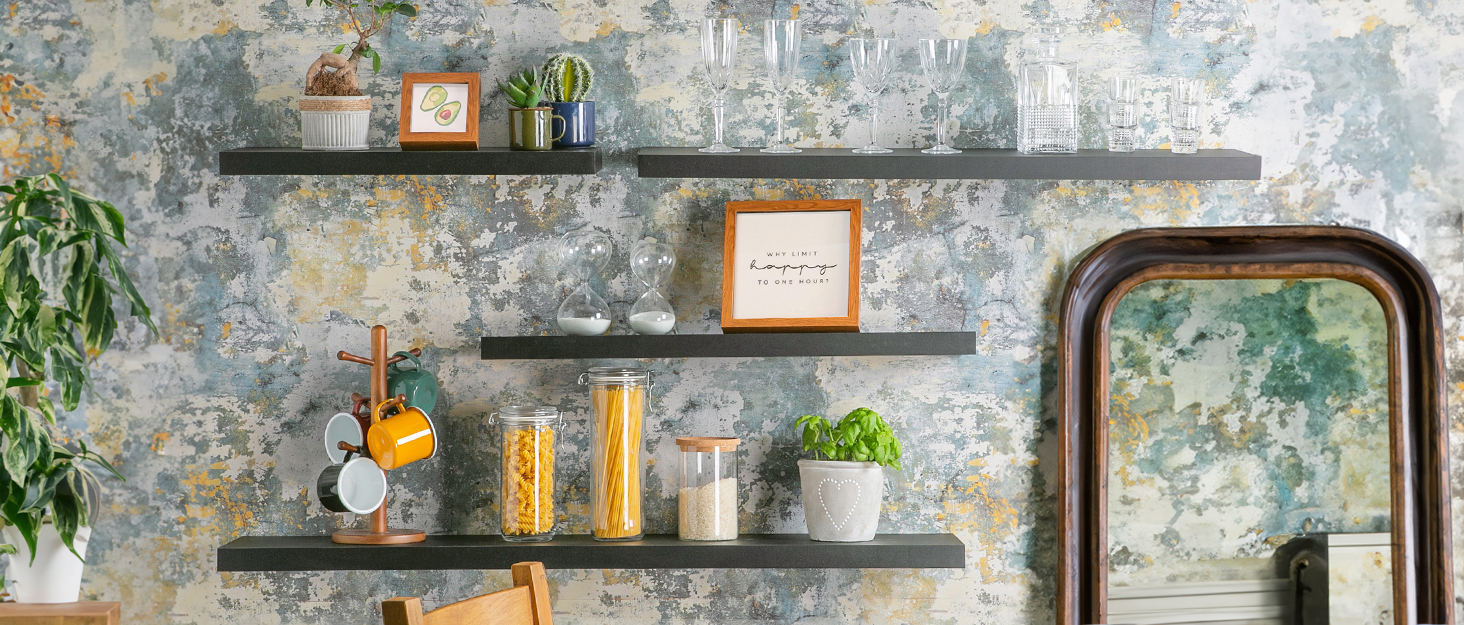 Rustic interior with three floating dark wooden shelves mounted on textured wall. Shelves display various decorative items and plants.